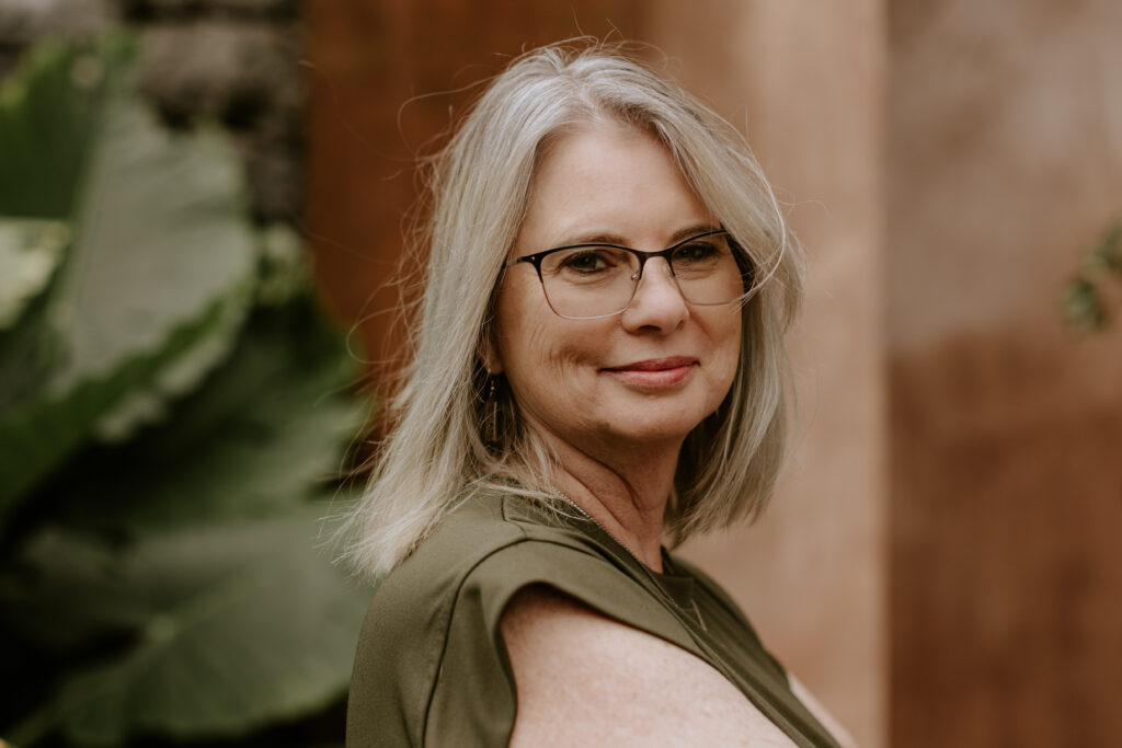 Female with glasses, blonde hair with greenery to the left